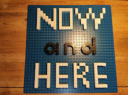 Schrift Now and Here mit Lego geschrieben als Hinweis auf Achtsamheit